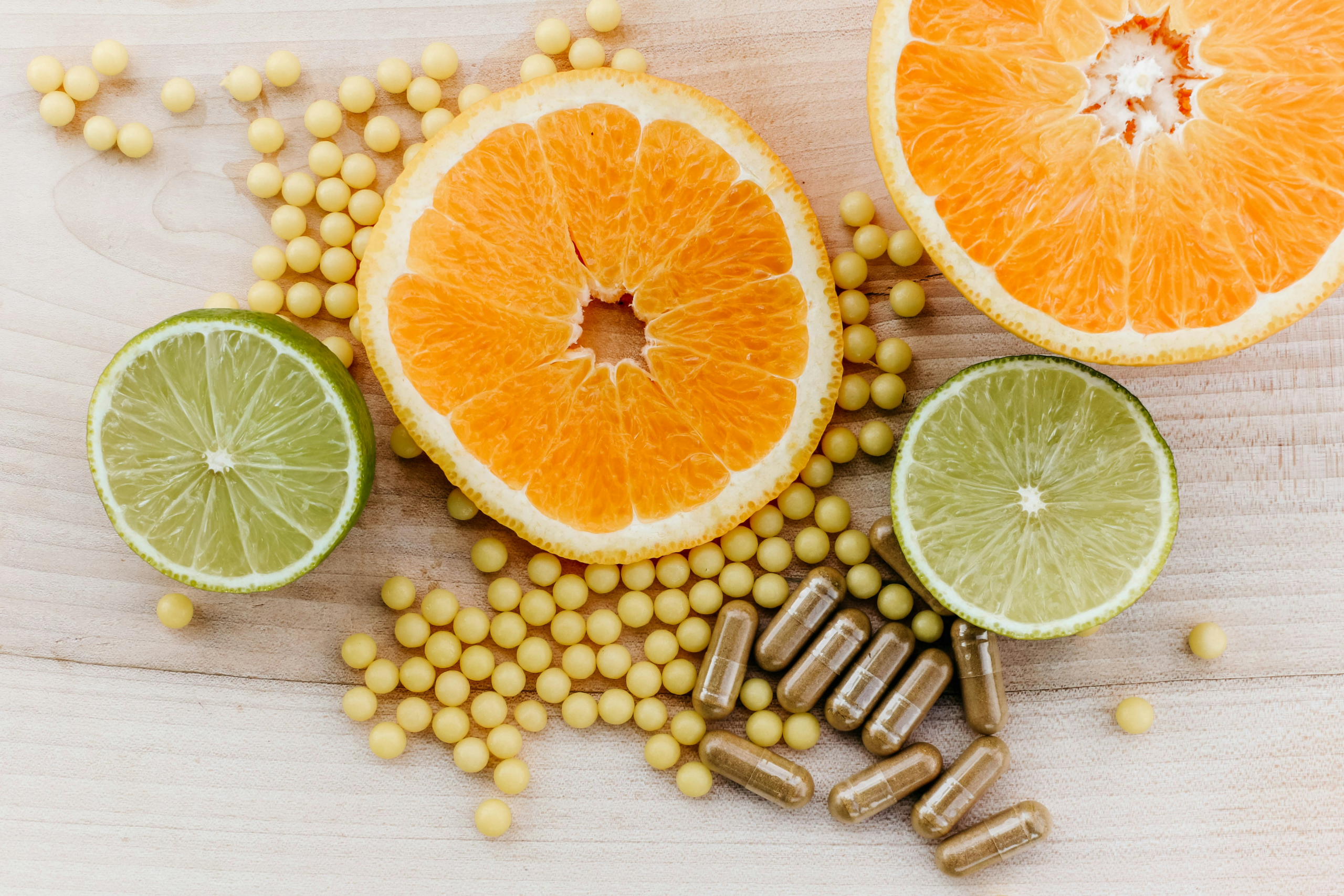 Capsules and pills with sliced oranges on wooden board
